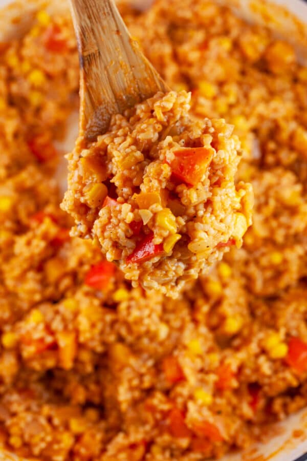 Wooden spoonful of cooked Spanish rice lifted from Dutch oven.
