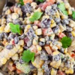Black bean corn salad garnished with fresh cilantro in ceramic bowl with spoon.