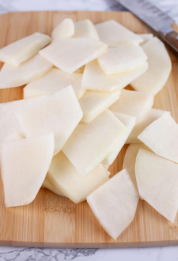 Kohlrabi slices on wooden cutting board with knife.