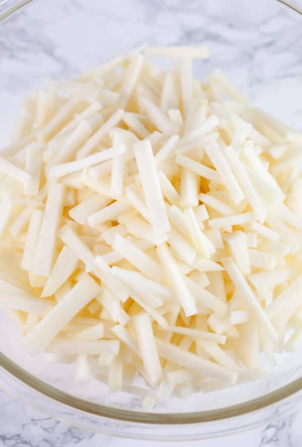 Thinly sliced kohlrabi in glass bowl.