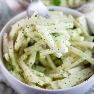 Forkful of cilantro lime kohlrabi slaw lifted from white bowl.