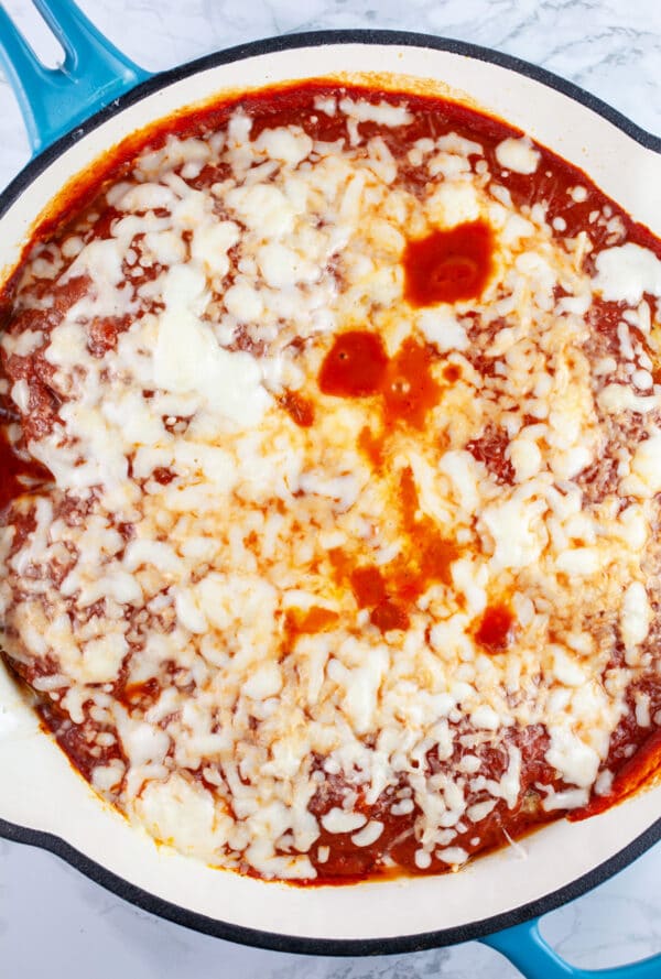 Chicken Parmesan with melted cheese in cast iron skillet.