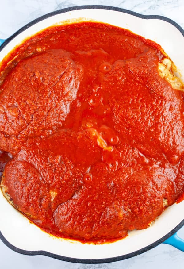 Cooked chicken Parmesan with marinara sauce in cast iron skillet.