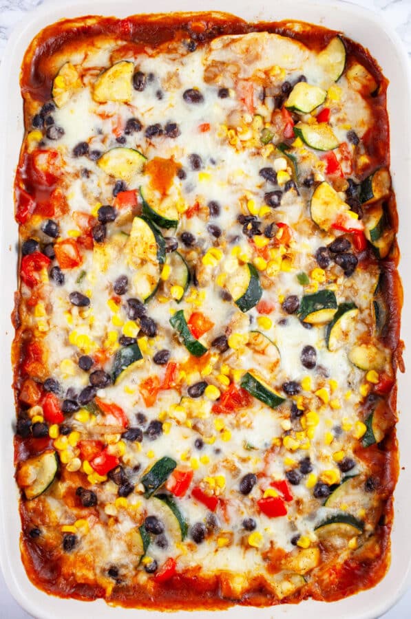 Baked enchilada casserole in ceramic baking dish.