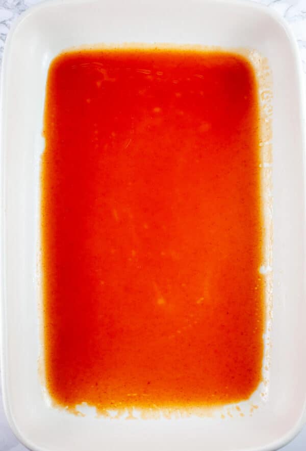 Red enchilada sauce in ceramic casserole dish.