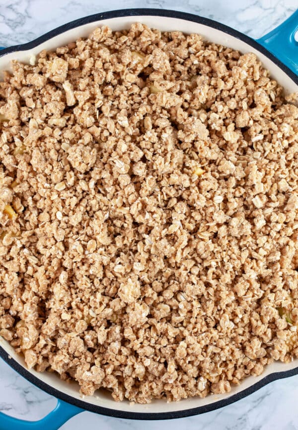 Uncooked apple crisp with streusel in cast iron skillet.