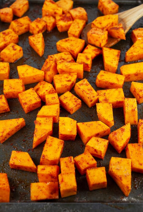 Uncooked butternut squash cubes on baking sheet.