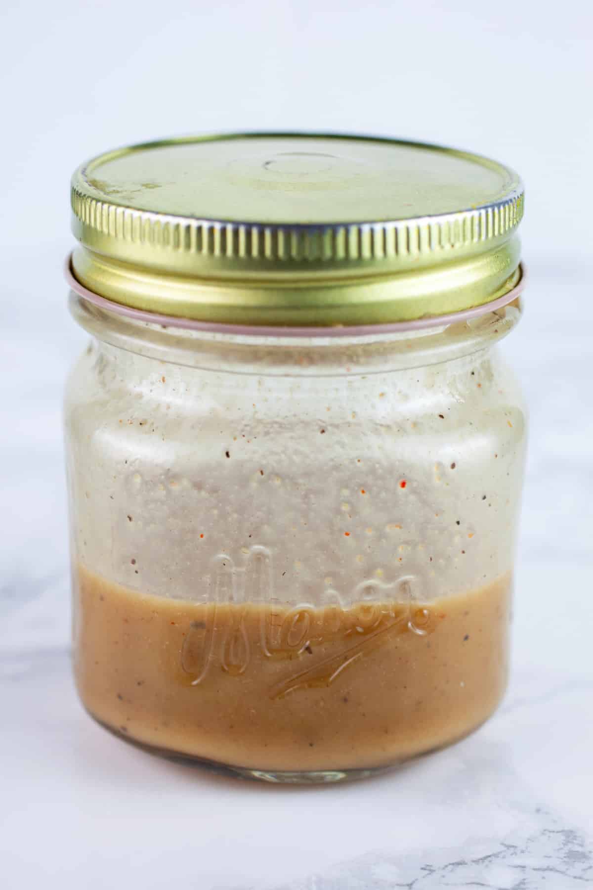 Maple Dijon dressing in small mason jar with lid.