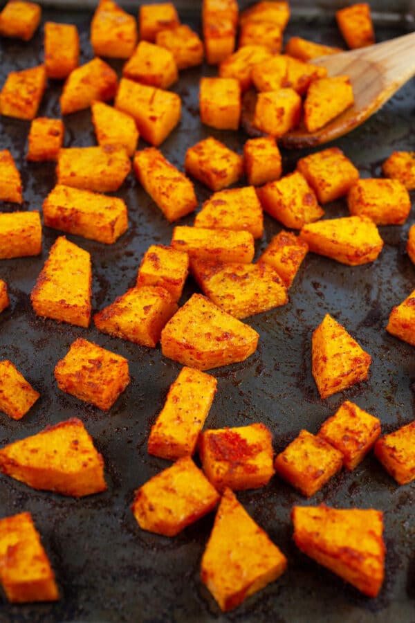 Roasted butternut squash cubes on baking sheet.