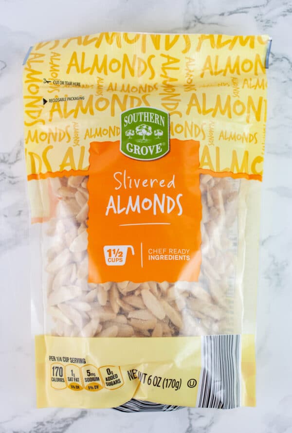 Unopened bag of slivered almonds on white surface.