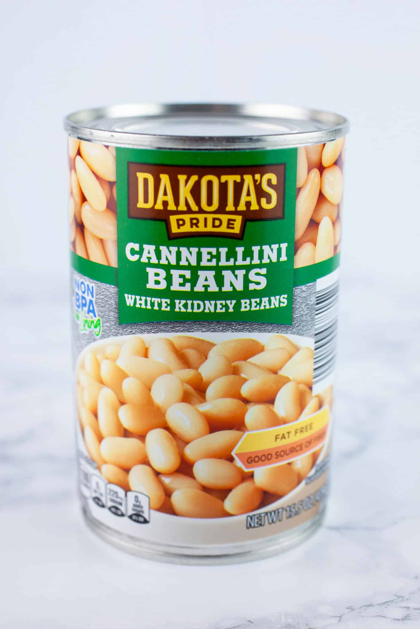 Unopened can of cannellini beans on white surface.