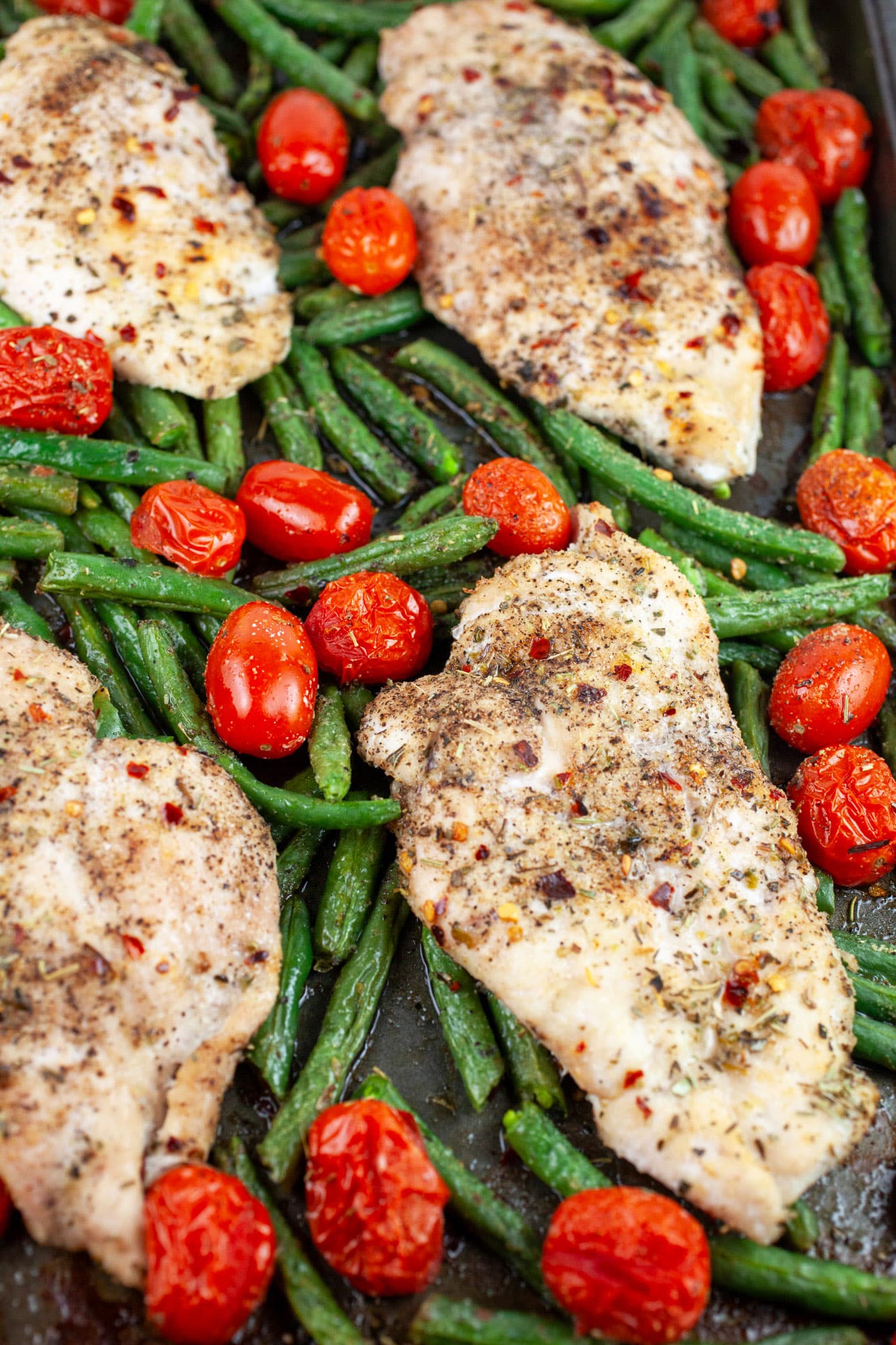 Sheet pan Italian chicken with green beans and tomatoes on baking sheet.