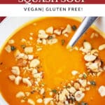 Curried butternut squash soup with peanut topping in white bowl with spoon.