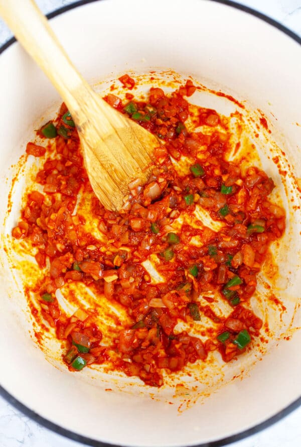 Garlic, onions, and jalapenos sauteed with Thai red chili paste in Dutch oven with wooden spoon.