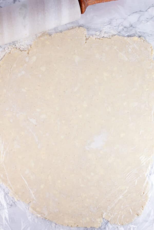 Gluten free pie dough rolled out on white surface.