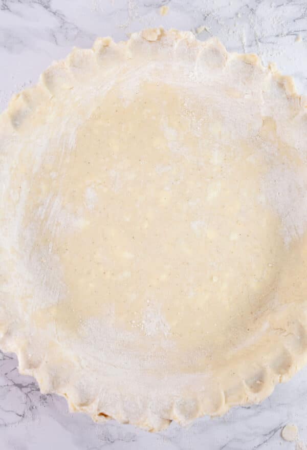Crimped, unbaked gluten free pie dough in pie plate.