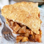 Slice of gluten free apple pie on white plate with fork.