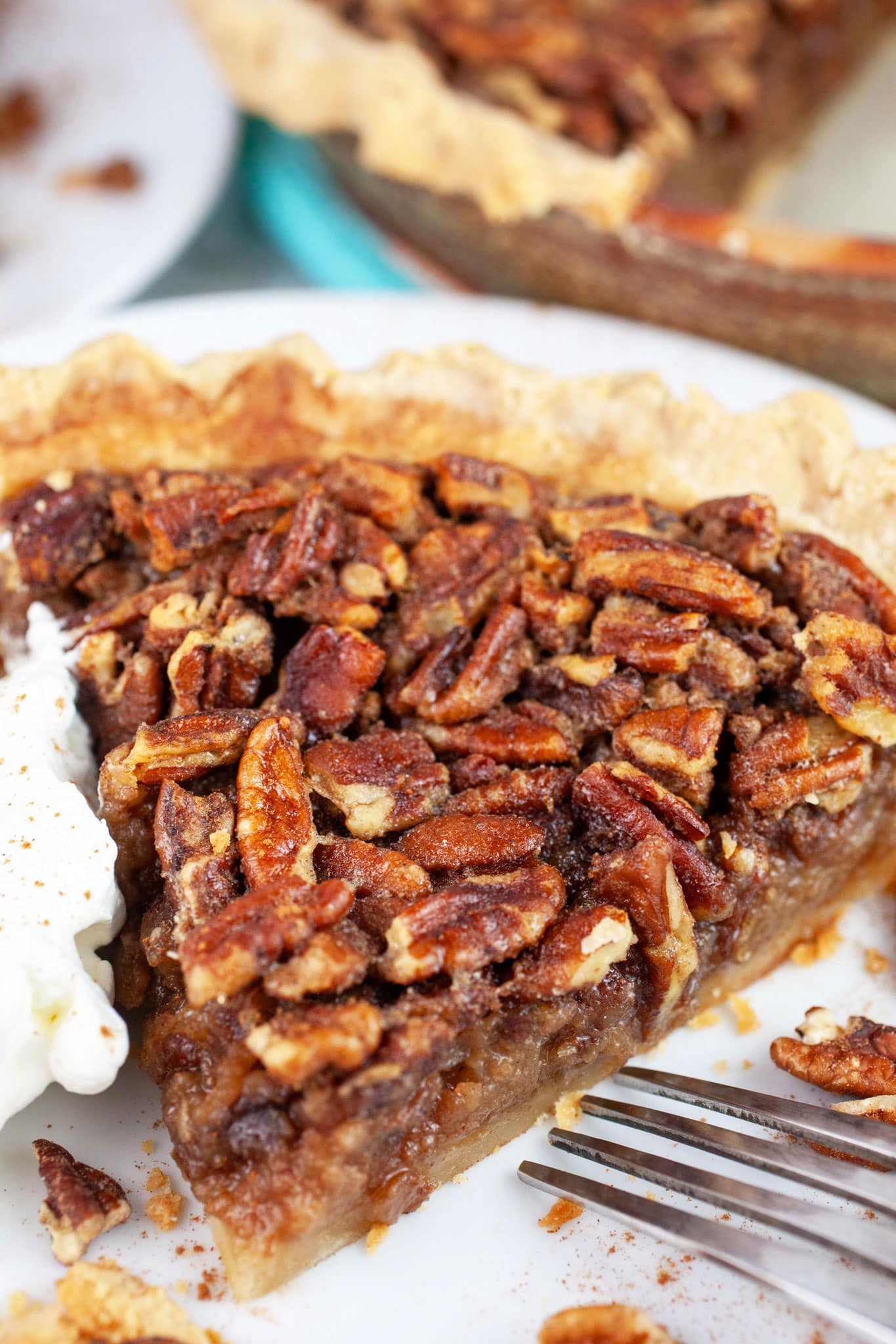 Maple bourbon walnut pie with whipped cream on white plate with fork.