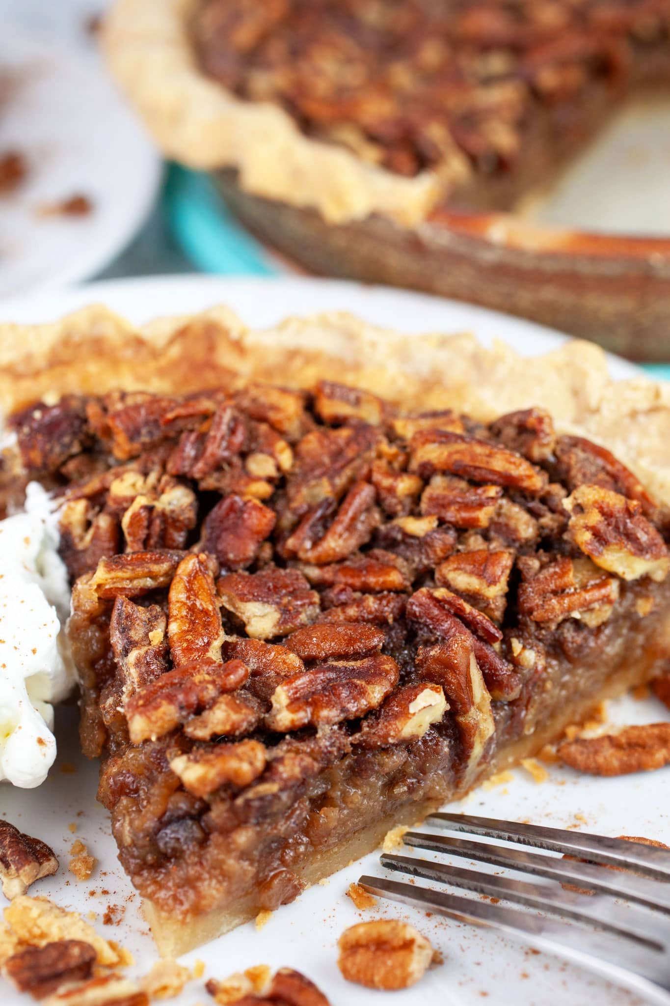 Slice of maple bourbon pecan pie on white plate with fork.