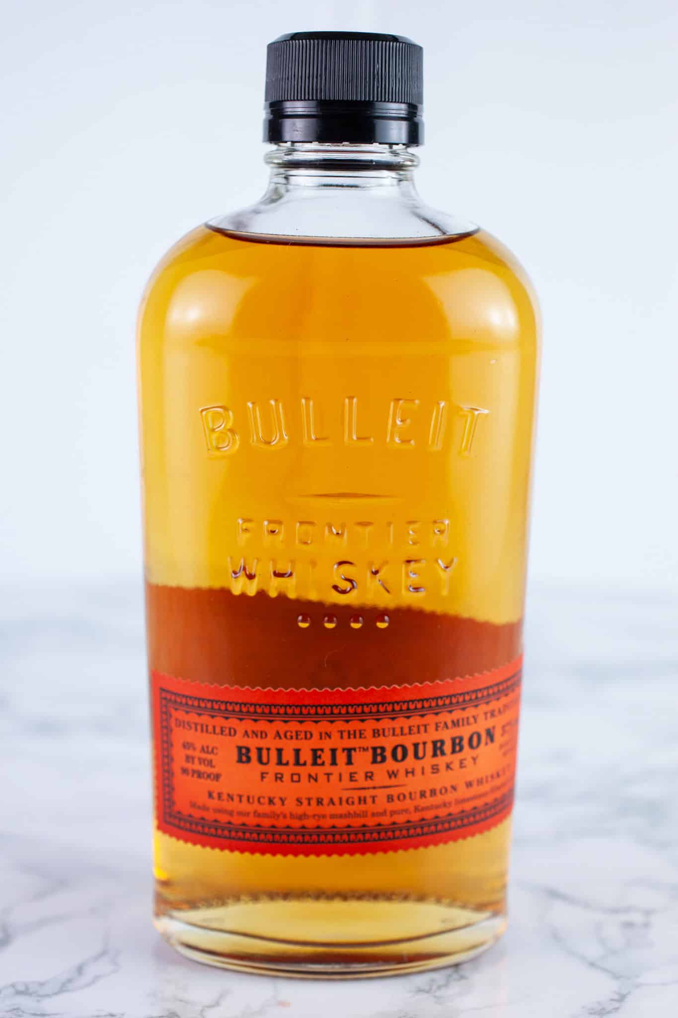 Bottle of unopened bourbon on white surface.