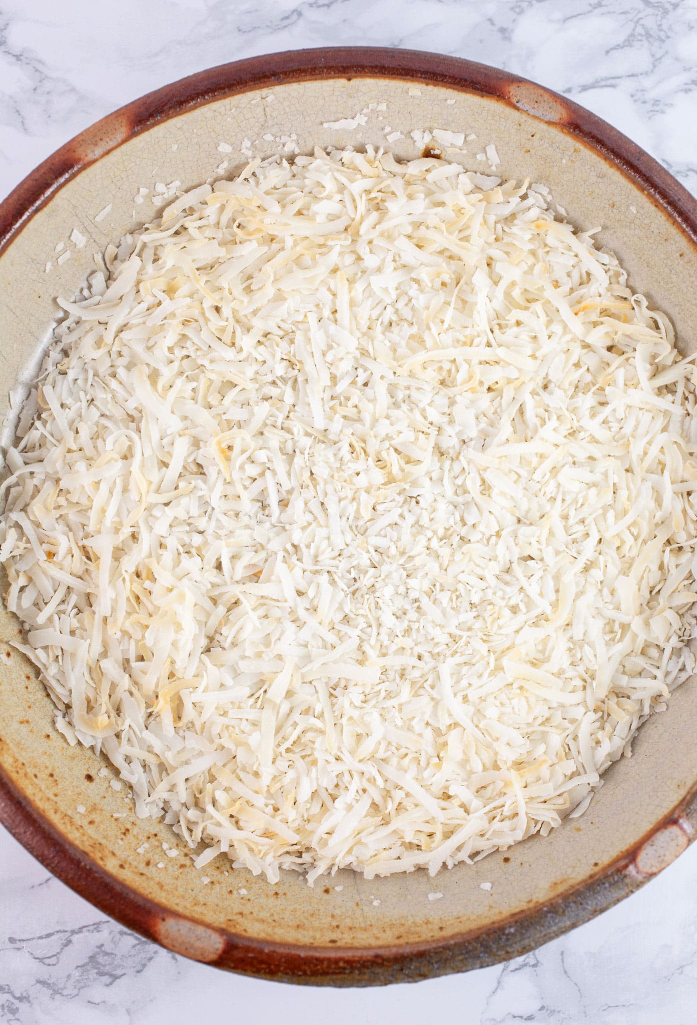 Toasted shredded coconut in ceramic pie plate.