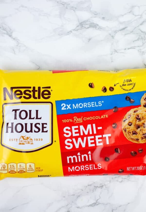 Unopened bag of semi-sweet mini chocolate chips on white surface.