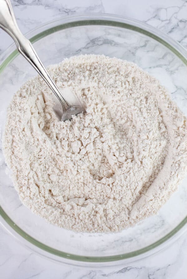 Dry ingredients in glass bowl with spoon.