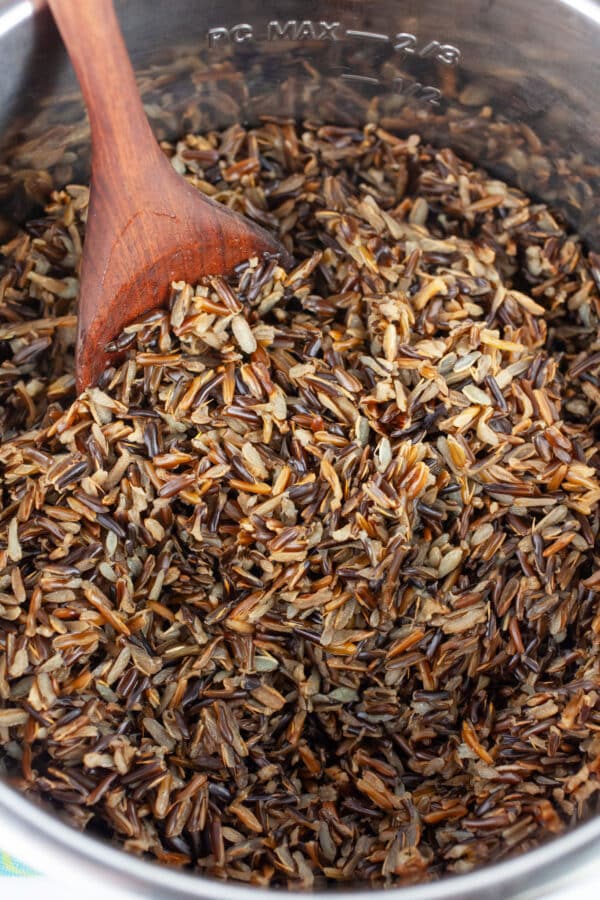 Cooked wild rice with wooden spoon in Instant Pot.