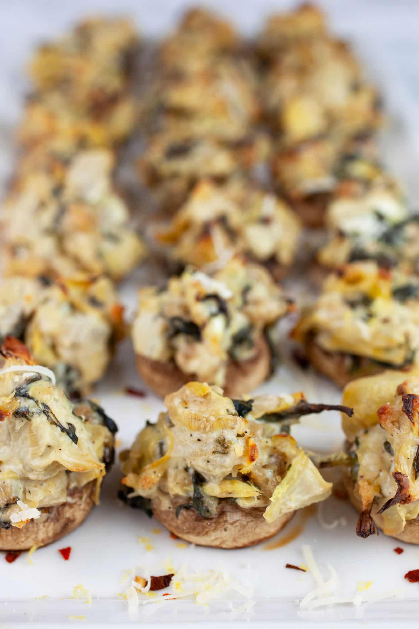Spinach artichoke stuffed mushrooms on white platter.