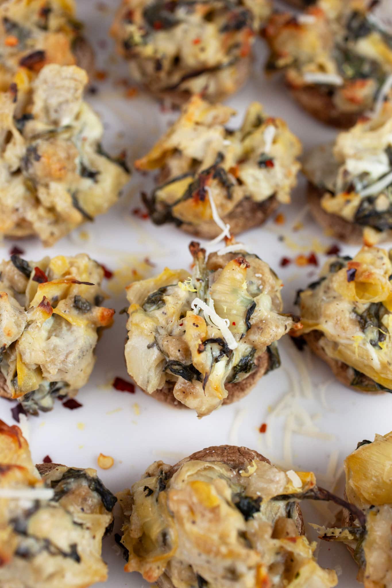 Spinach artichoke stuffed mushrooms on white platter.