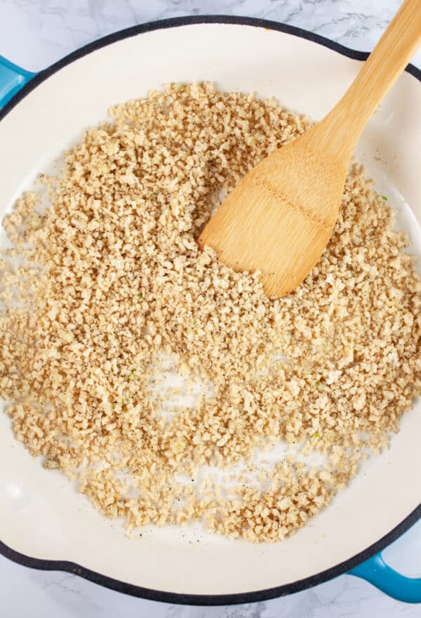 Gluten free Panko breadcrumbs toasted in skillet with wooden spatula.
