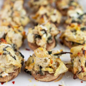 Spinach artichoke stuffed mushrooms on white platter.