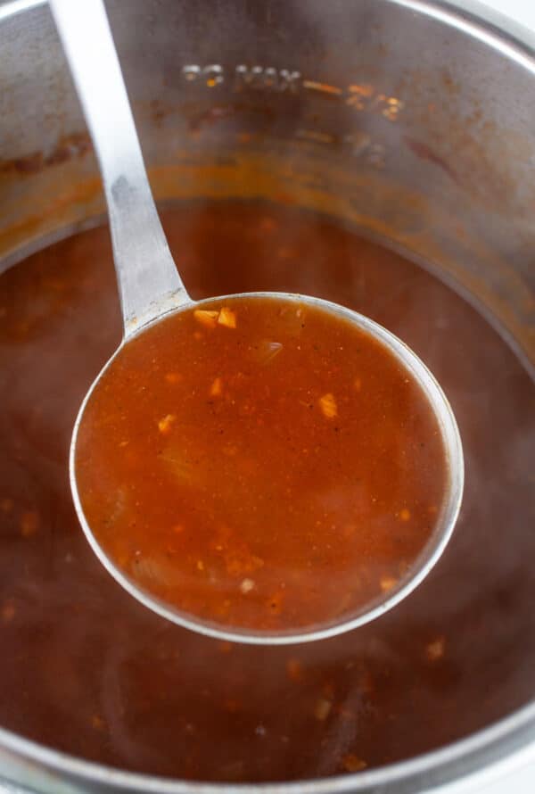 Scoop of gravy lifted from Instant Pot on metal ladle.