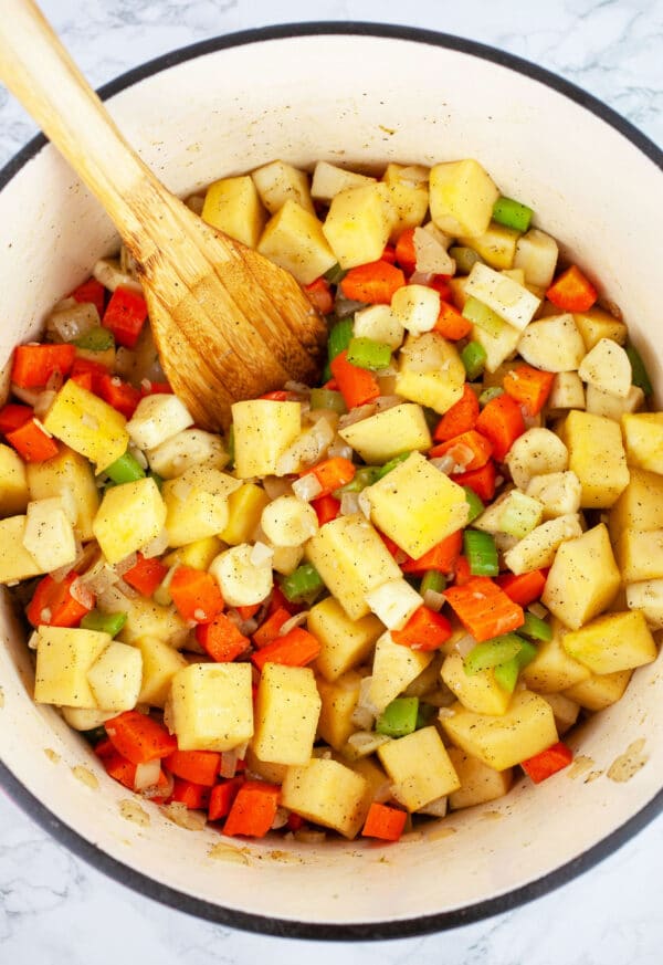 Diced vegetables sauteed in Dutch oven with wooden spoon.