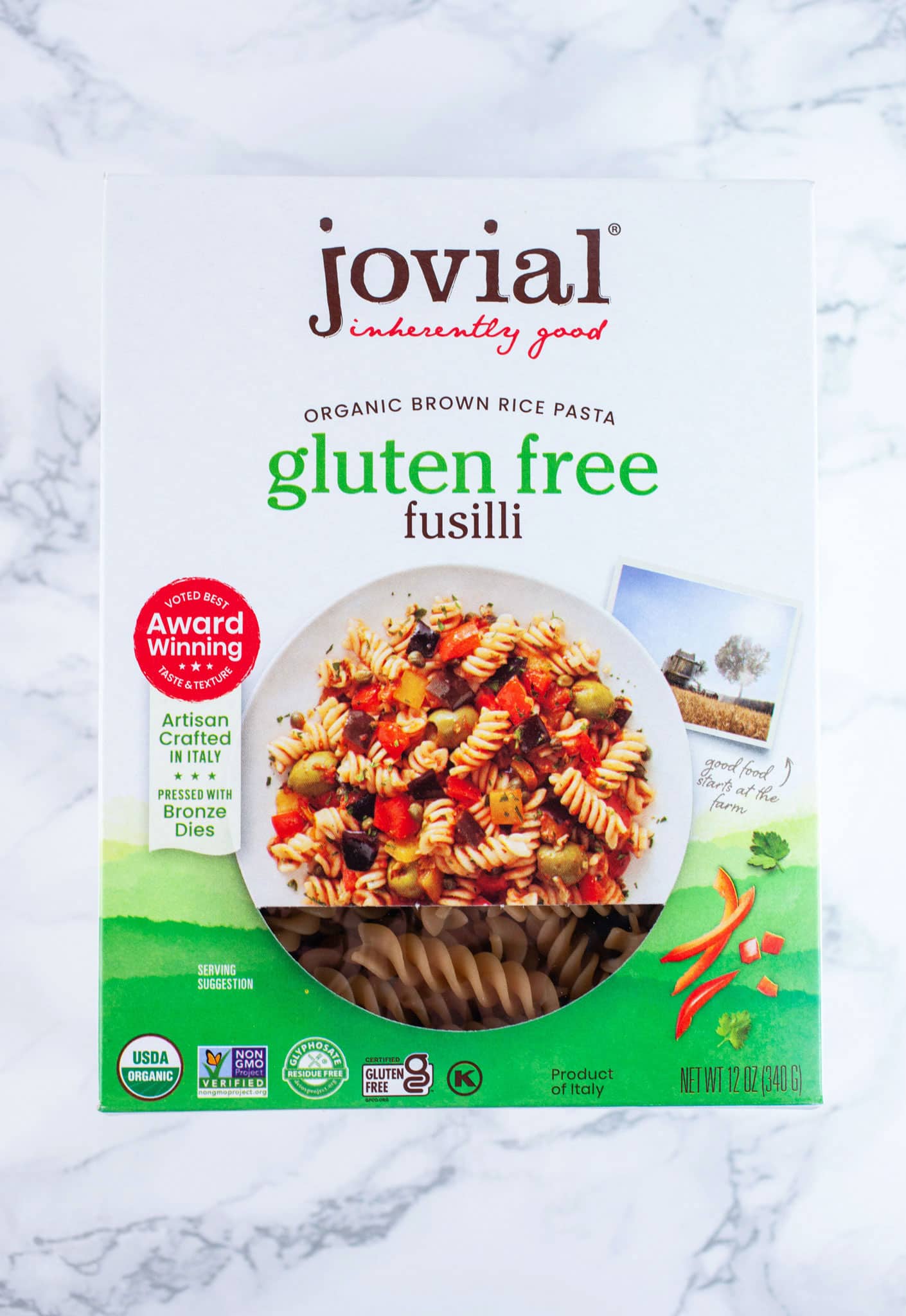 Unopened box of Jovial gluten free fusilli pasta on white surface.