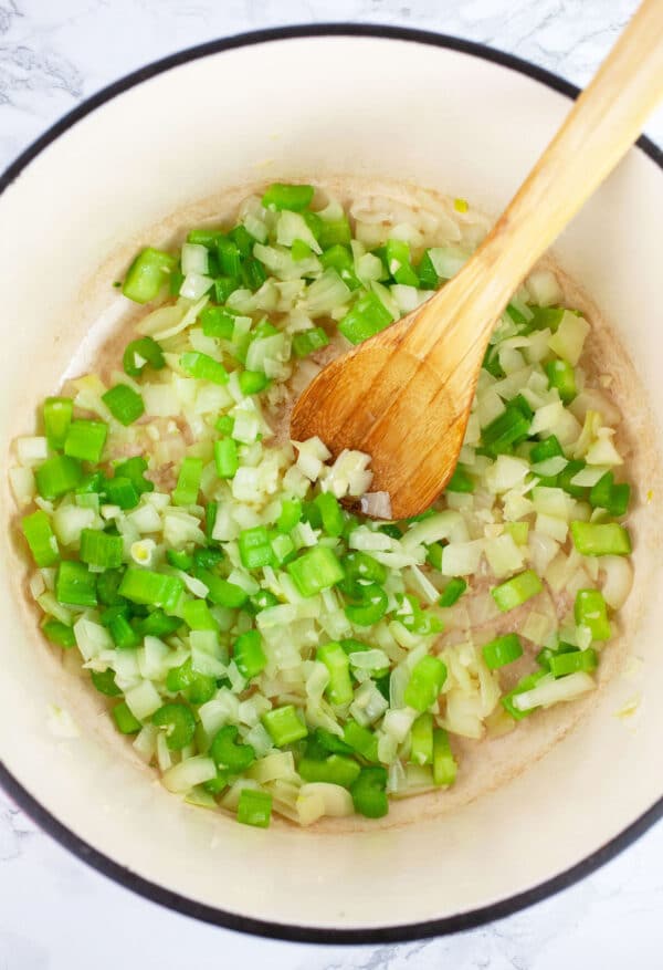 Minced garlic, onions, and celery sauteed in Dutch oven with wooden spoon.