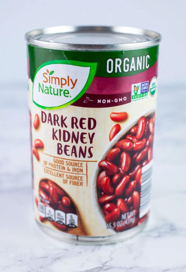 Unopened can of kidney beans on white surface.