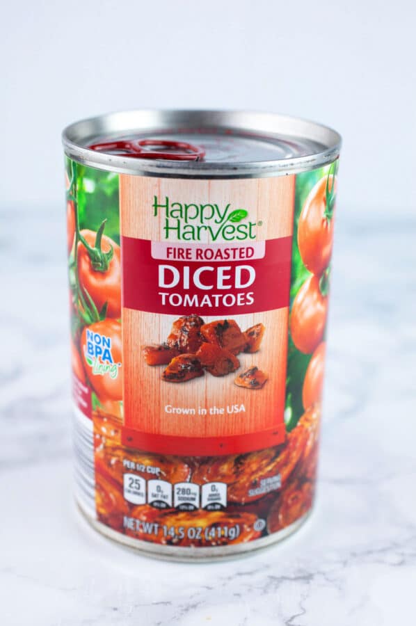 Unopened can of fire roasted tomatoes on white surface.