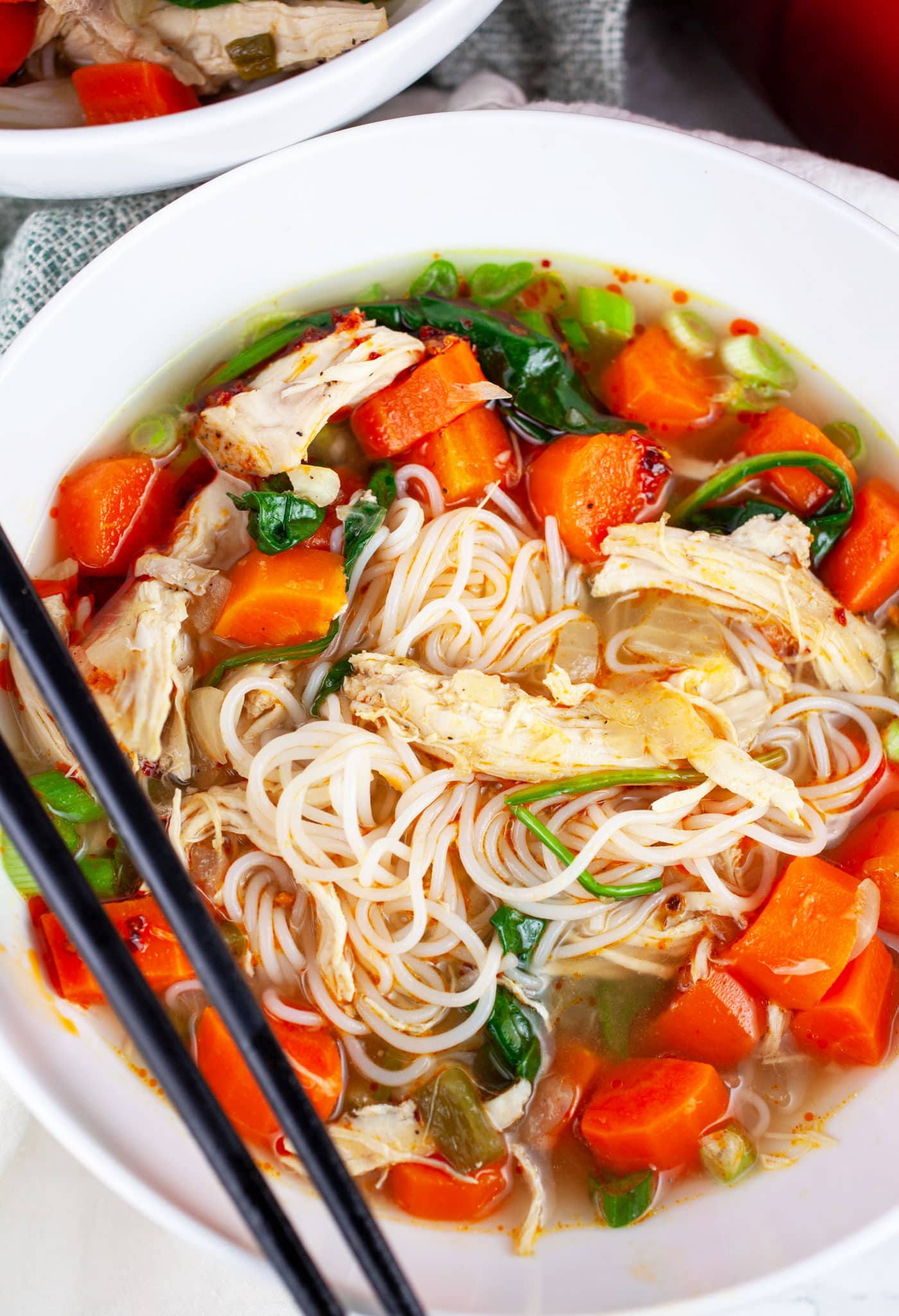 Bowl of Asian chicken noodle soup with chopsticks.