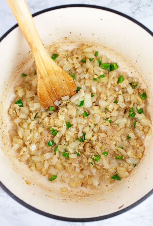 Minced garlic, onions, ginger, and jalapenos sauteed in Dutch oven with wooden spoon.