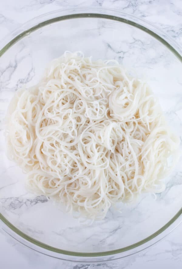 Cooked rice noodles in large glass bowl.