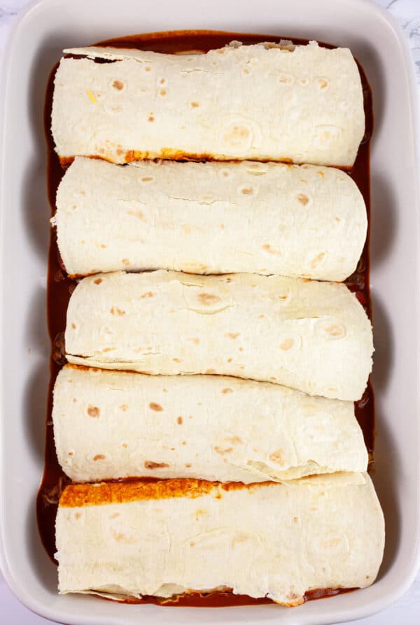Filled tortillas in ceramic casserole dish.