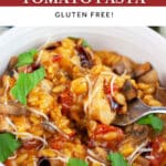 Chicken mushroom tomato pasta garnished with Parmesan cheese, balsamic glaze, and fresh basil in white bowl with fork.