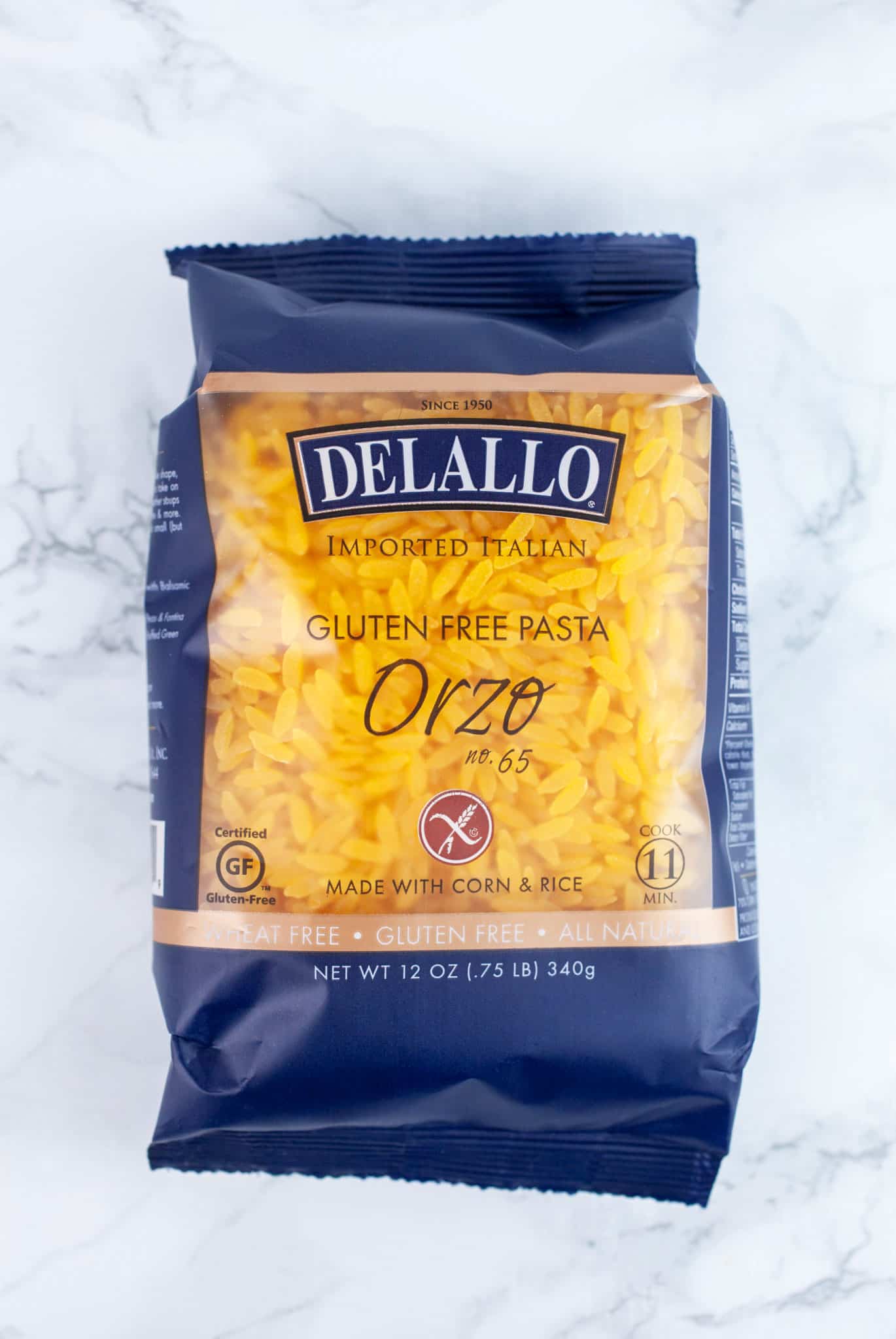Unopened package of gluten free orzo pasta on white surface.