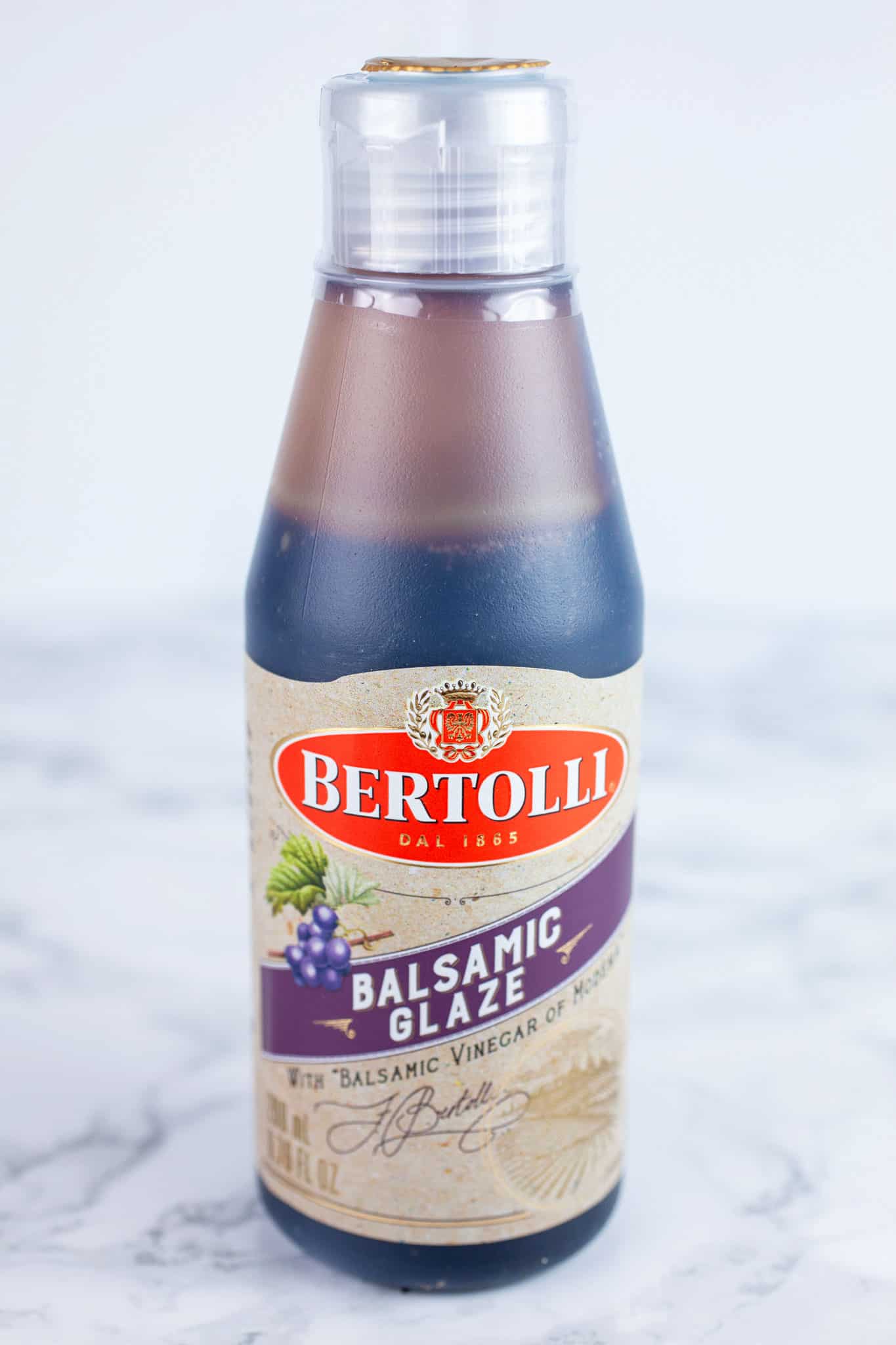 Unopened bottle of balsamic glaze on white surface.