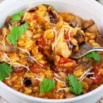Chicken mushroom tomato pasta garnished with fresh basil and balsamic glaze in white bowl with fork.