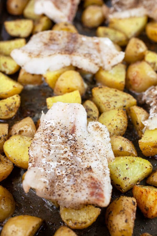 Roasted cod and potatoes on baking sheet.