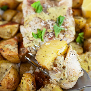 Pesto baked cod and potatoes with fork garnished with fresh basil.
