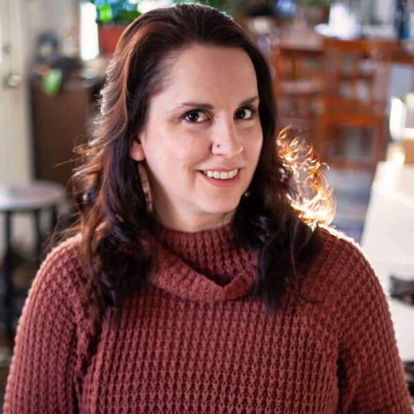 Brunette woman in kitchen wearing burgundy sweater.