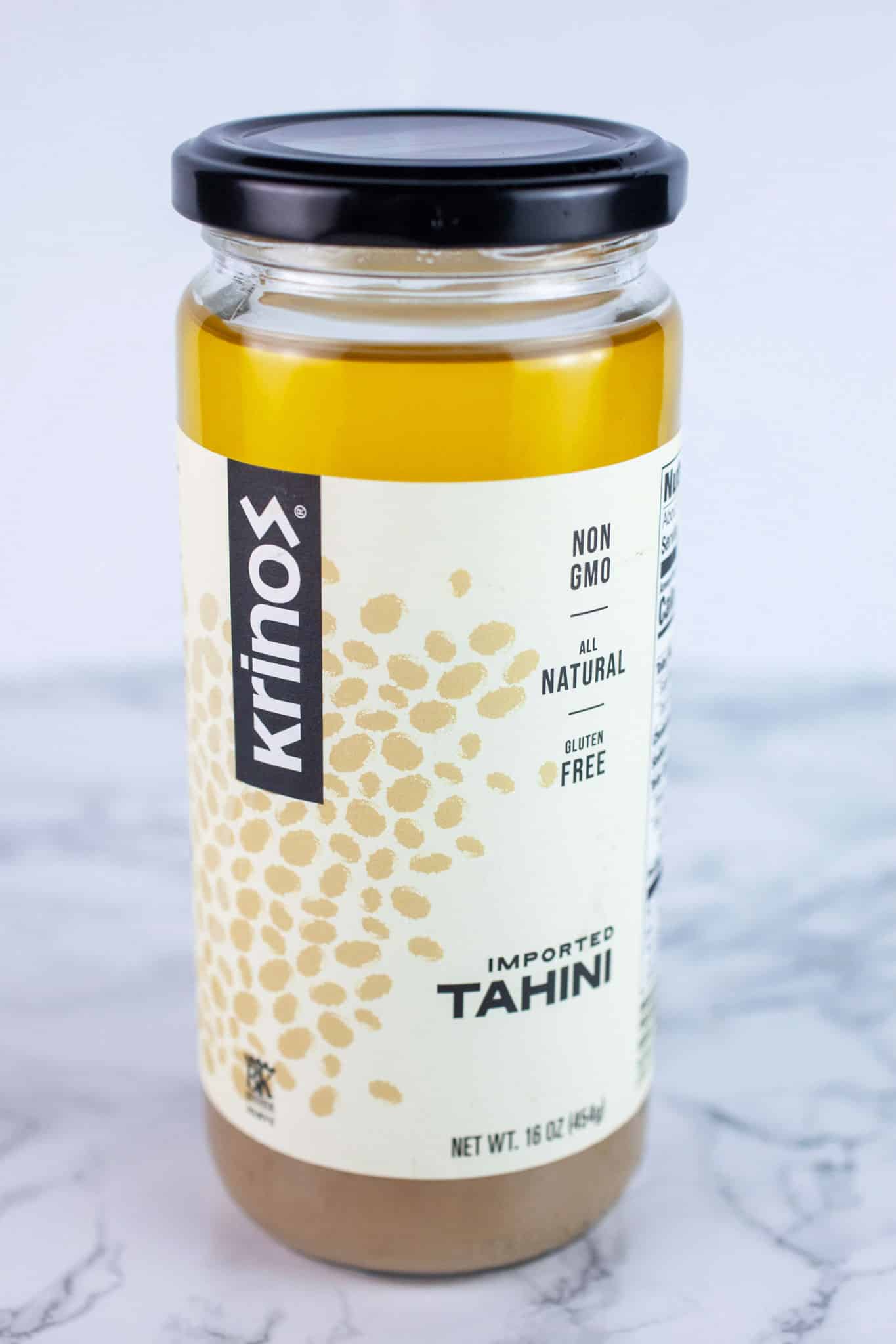 Unopened jar of tahini on white surface.